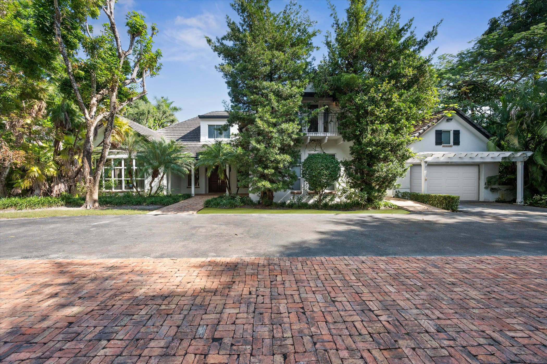 10001 SW 60th Court — front exterior with brick driveway and mature canopy