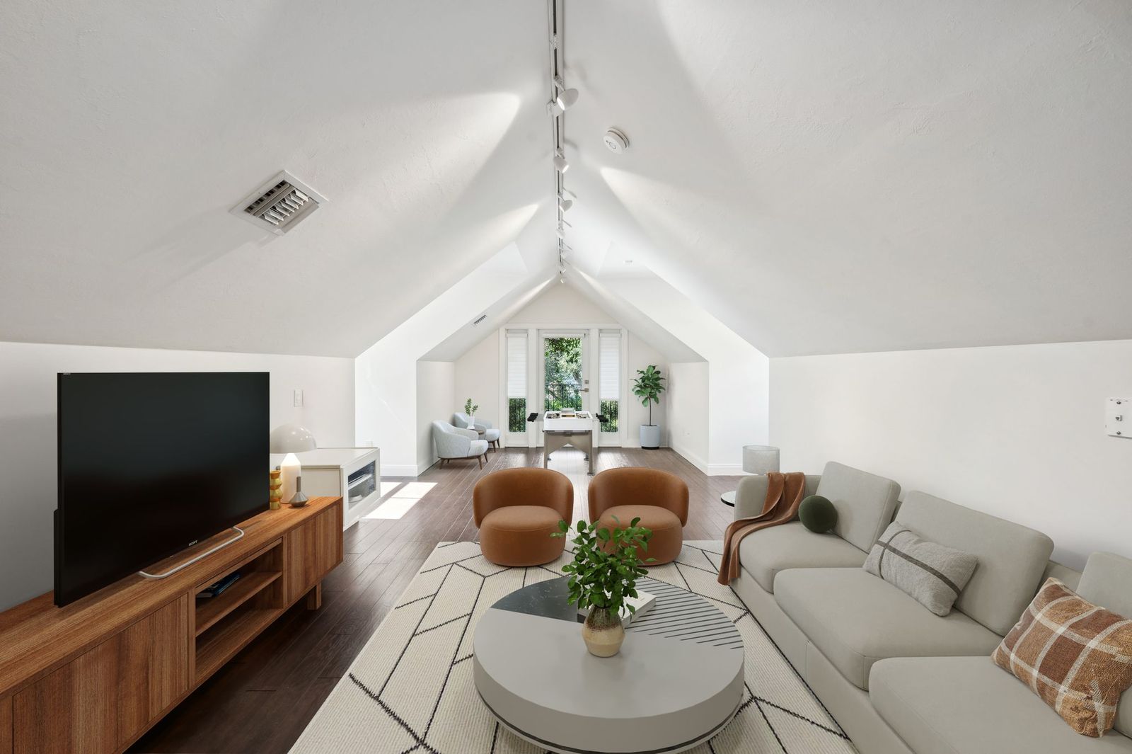 Vaulted ceiling bonus room with hardwood floors and media area