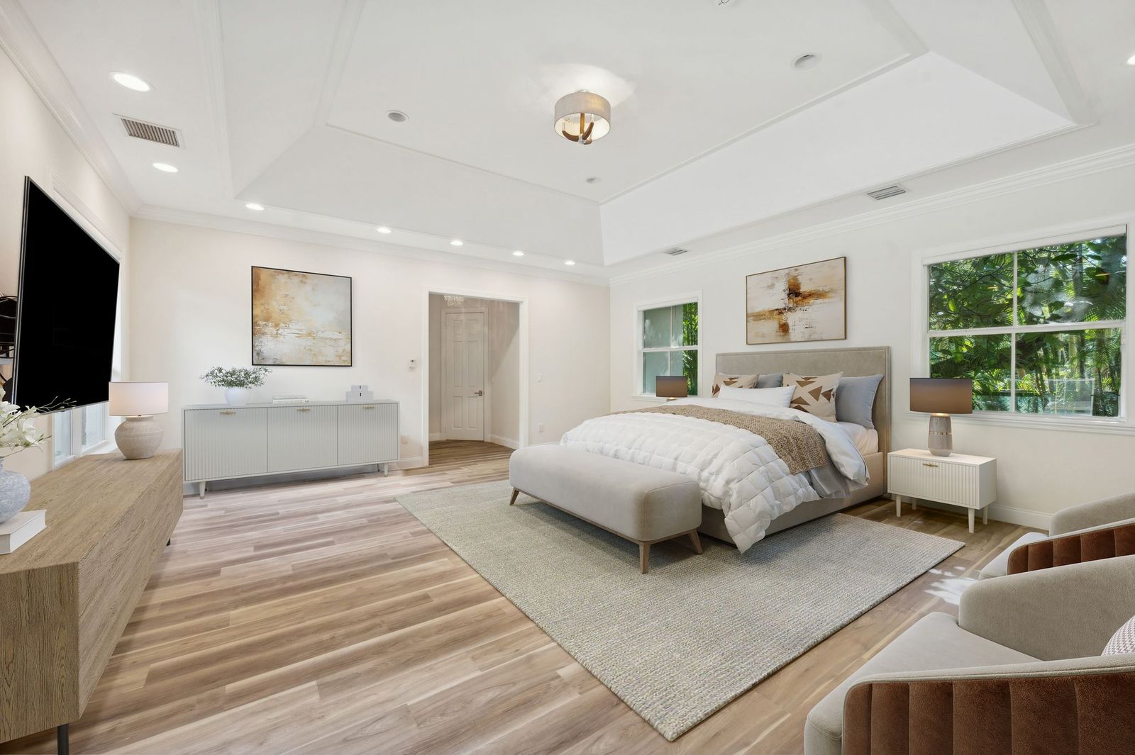 Primary bedroom with tray ceiling and hardwood floors